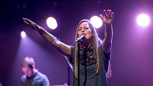 Female worship student sings under purple lights